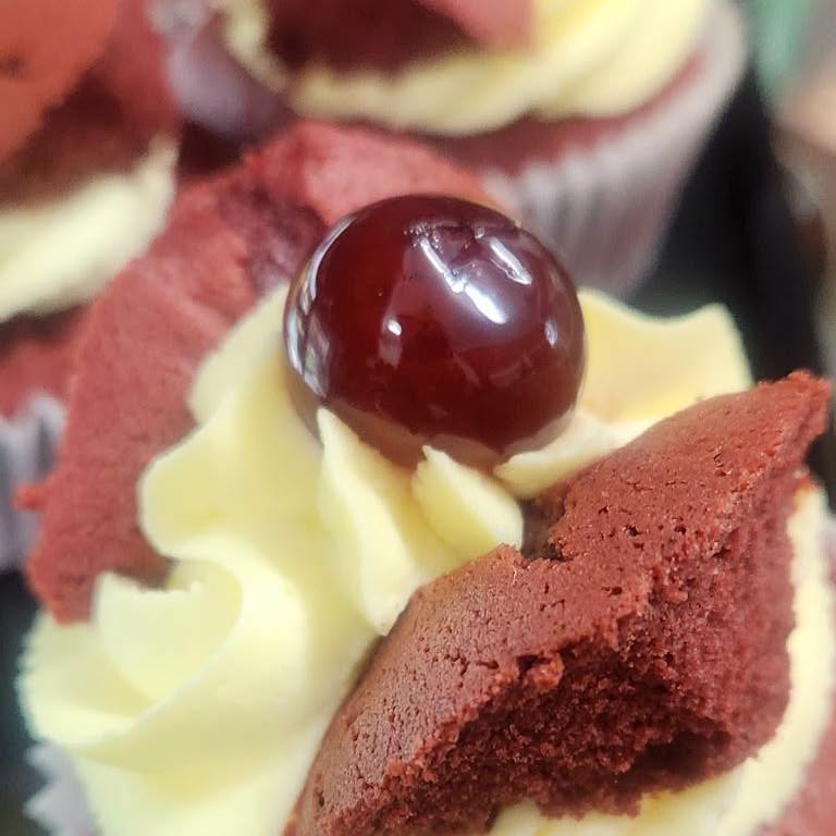 Red velvet cupcake with a cream swirl and a cherry