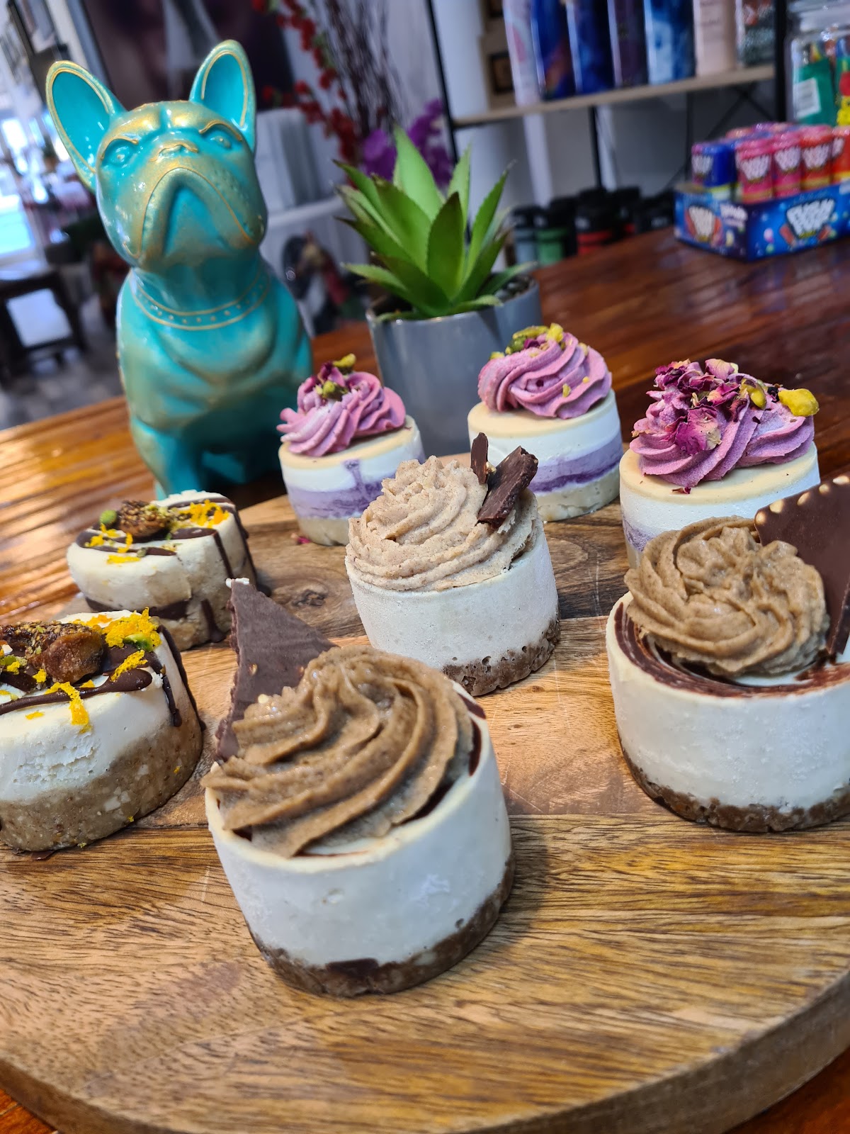 Mini cheesecakes on a wooden board beside a teal French bulldog ornament